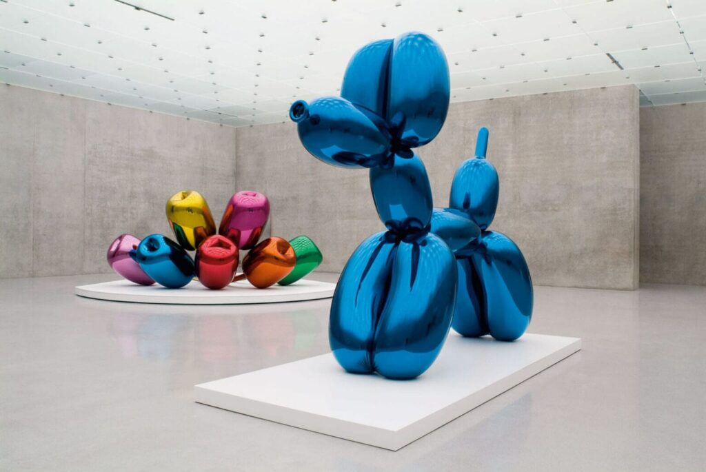 A monumental balloon dog blue by Jeff Koons next to his famous tulips in the background
