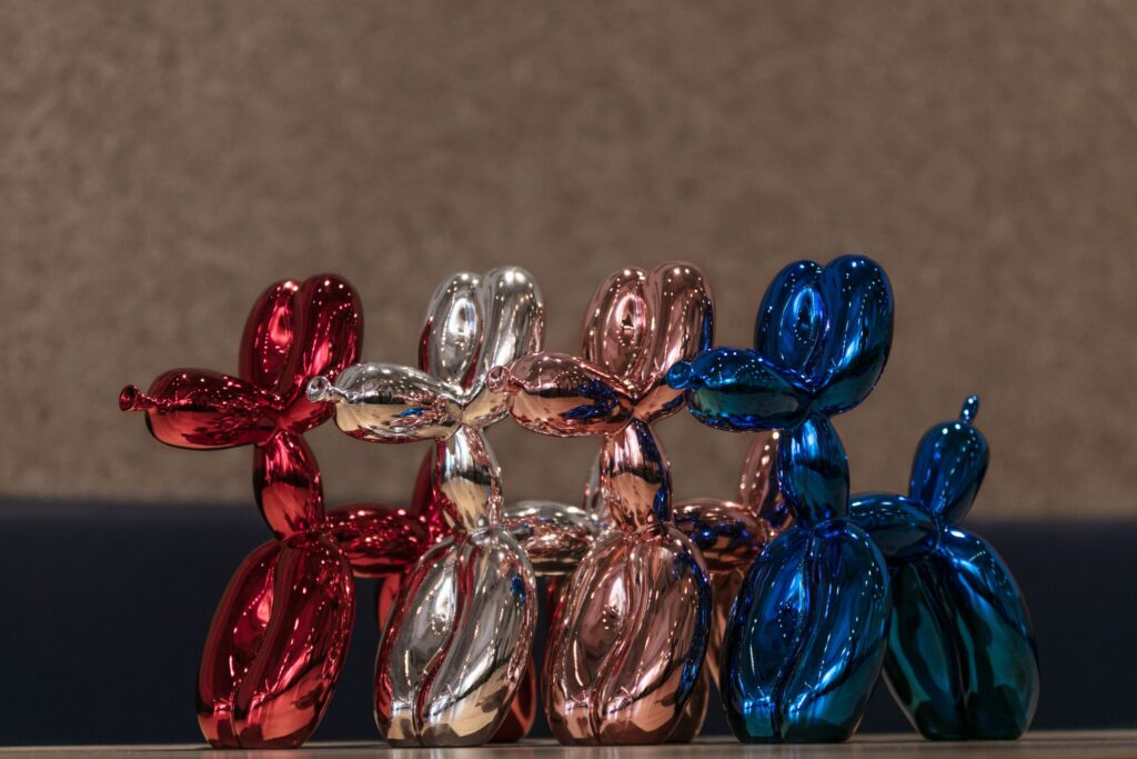 4 shiny balloon dogs by editions studio, one red, one silver, one rose gold and one blue